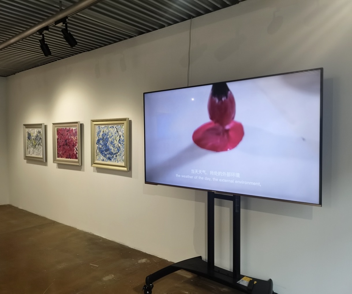 Artificial Emotions exhibition view with three paintings and a video display